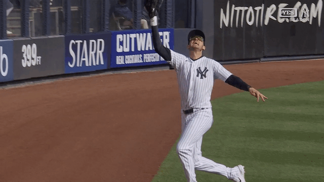 An animated gif of Cody Bellinger making a juggling, running catch on the warning track
