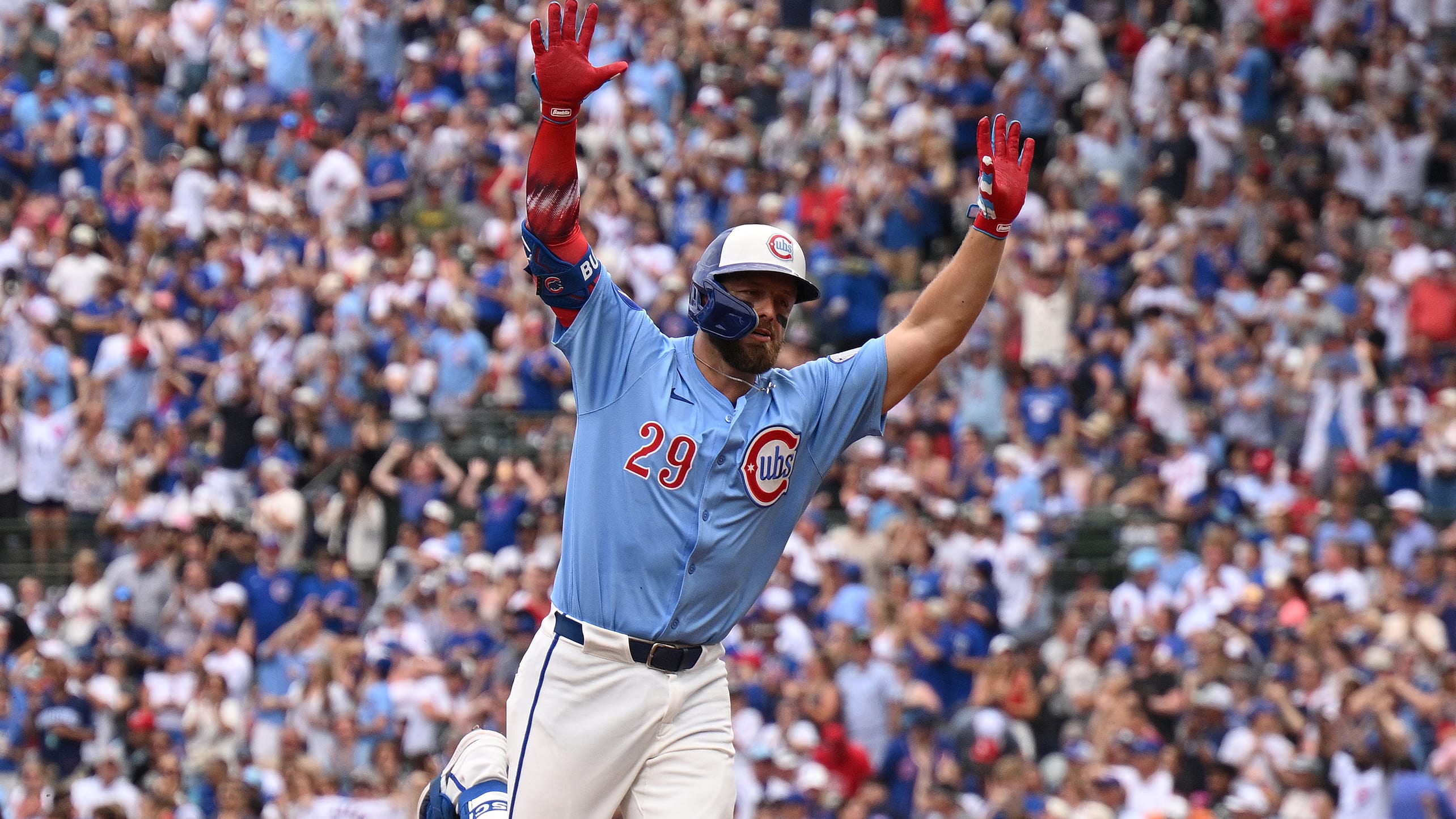 Michael Busch raises his arms rounding the bases on a home run