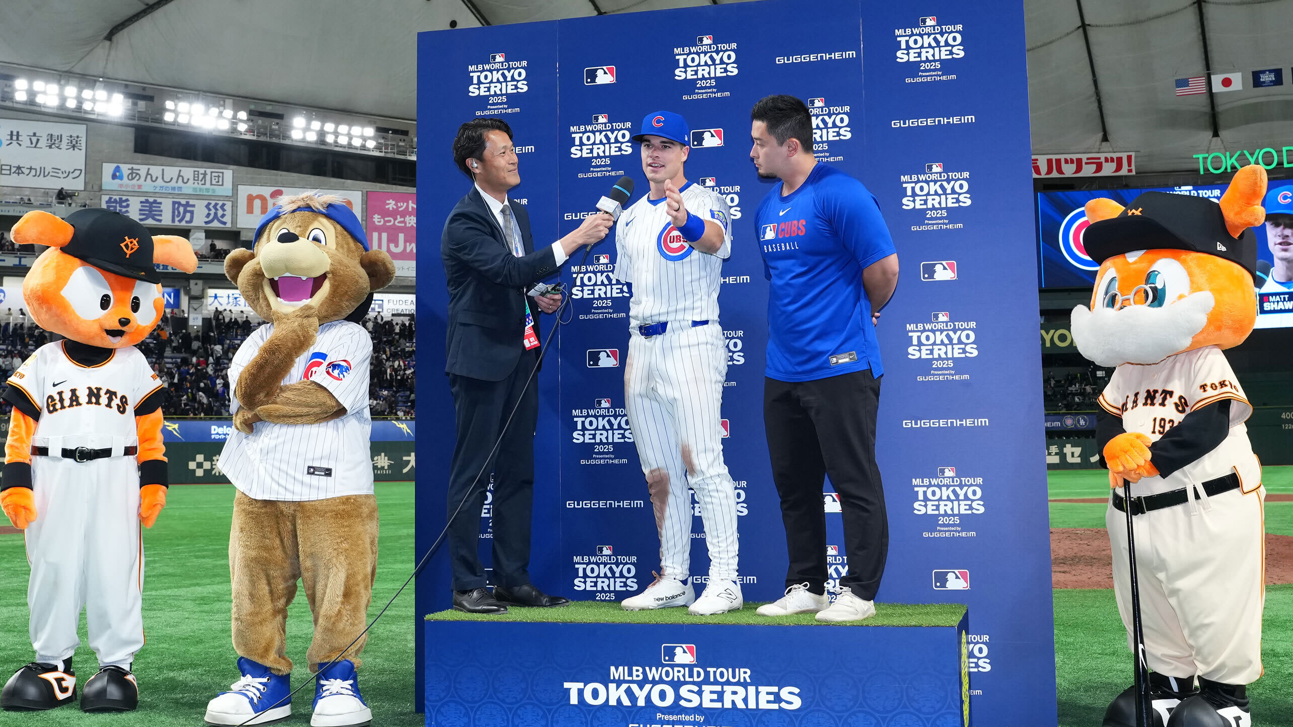 Matt Shaw is interviewed on a stage while surrounded by mascots