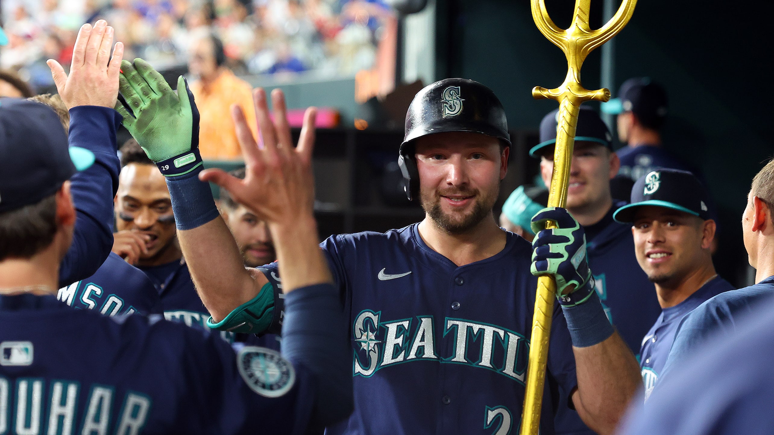 Cal Raleigh holds a trident in the dugout after hitting a home run