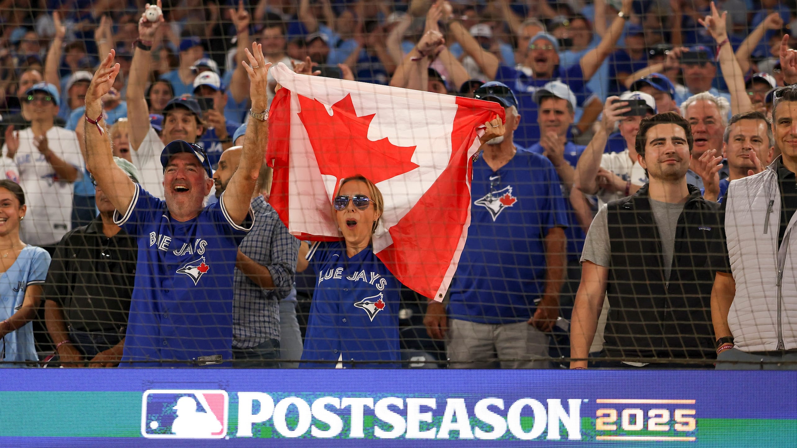 Blue Jays fans hold a Canadian flag during a 2025 playoff game