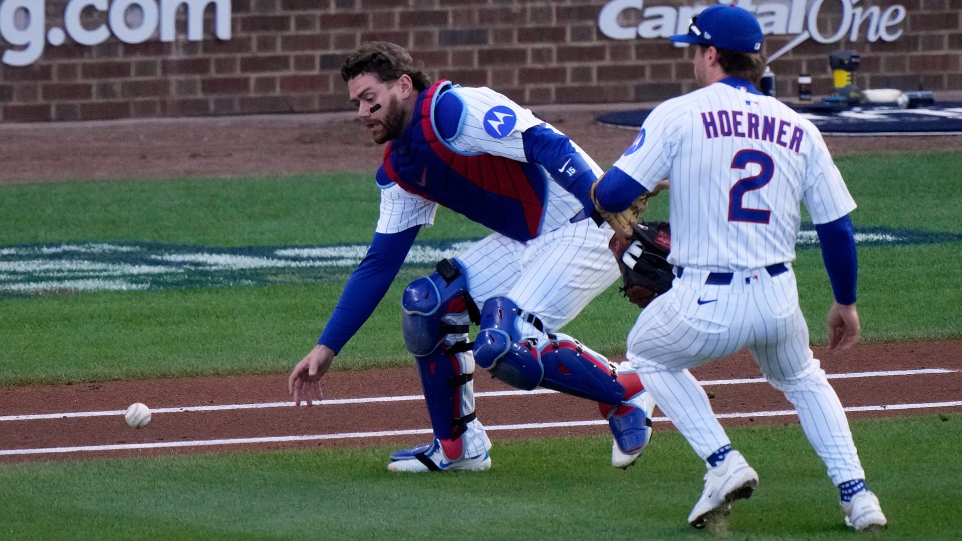 Cubs catcher Carson Kelly reaches for the ball after it drops near him and second baseman Nico Hoerner