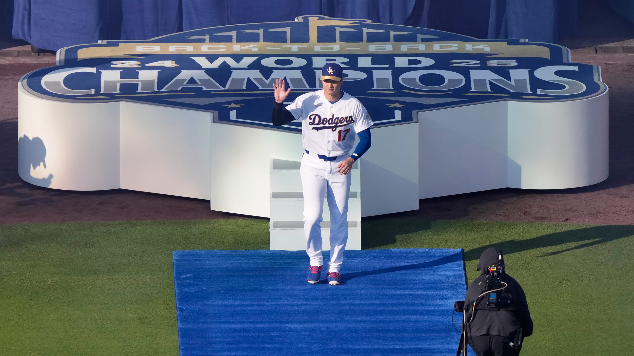 Shohei Othani waves as he's introduced pregame in front of a stage reading Back to Back World Champions