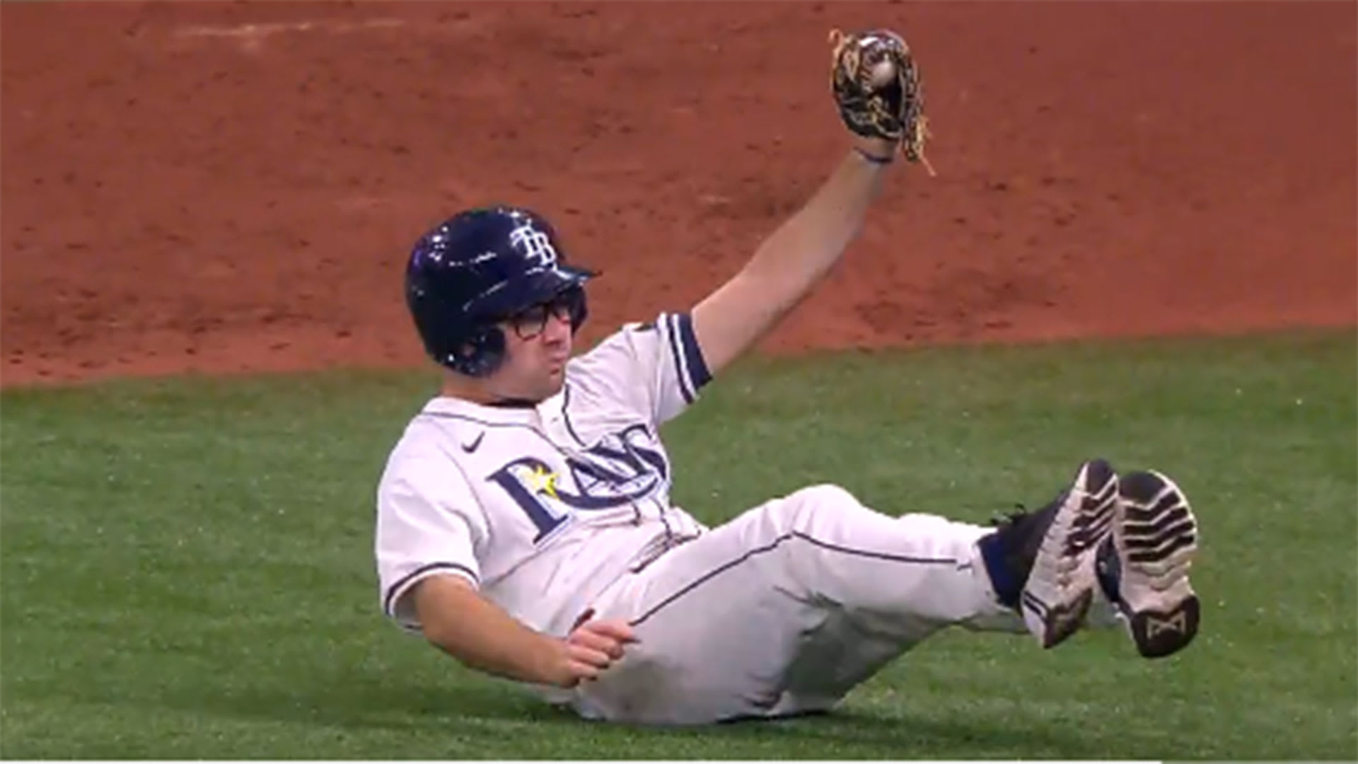 A Rays ballboy holds up a ball after a diving stop