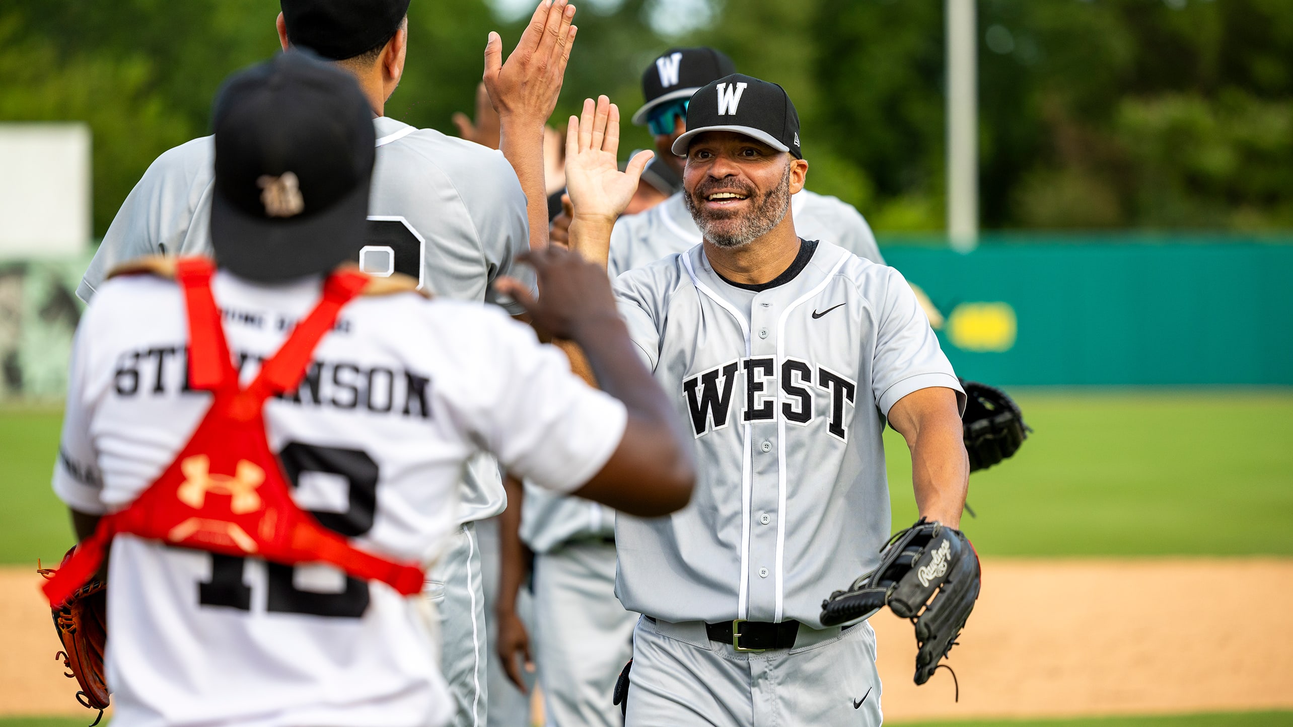 Scott Hairston high-fives West teammates after the 2025 East-West Classic