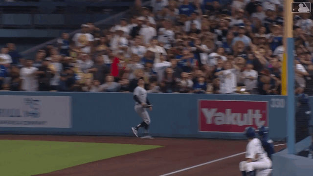 An animated gif of Mike Tauchman leaning over Dodger Stadium's short right-field wall to rob a home run