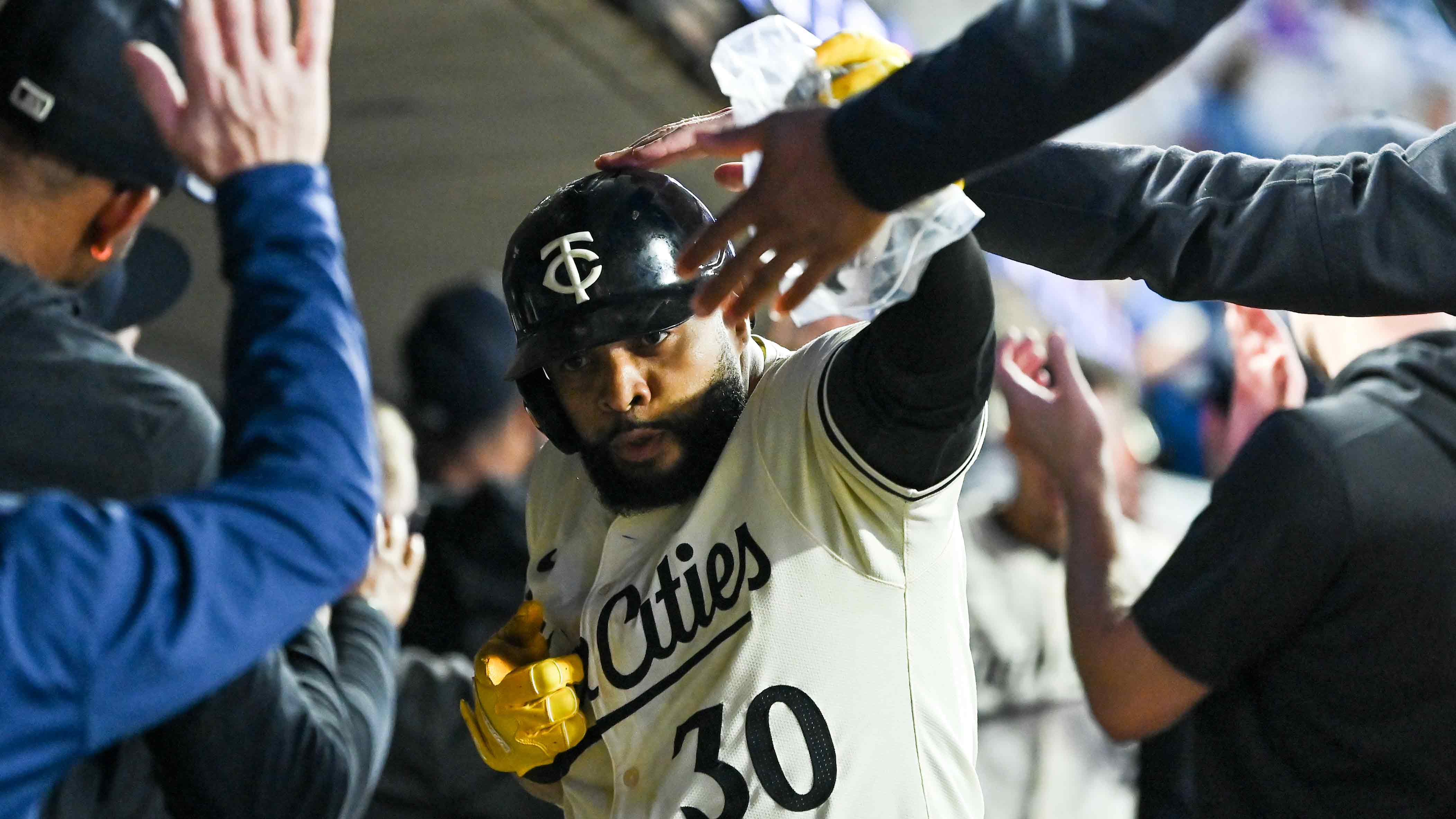 Carlos Santana celebrates a home run in the dugout with the Twins' Rally Sausage