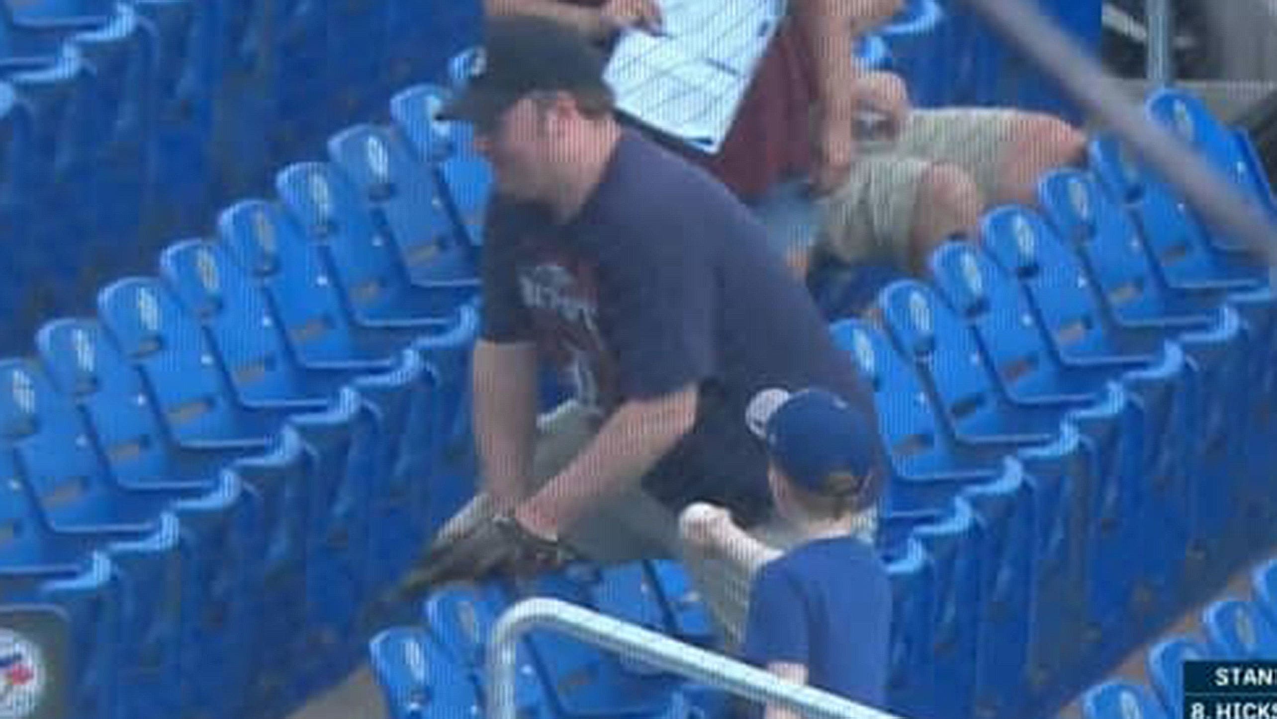 A young Blue Jays fan hands a ball to an adult Tigers fan