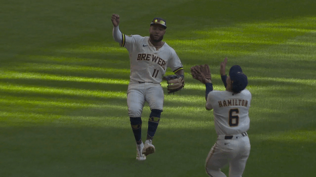 An animated gif of Brewers third baseman David Hamilton making an over-the-shoulder catch between two teammates