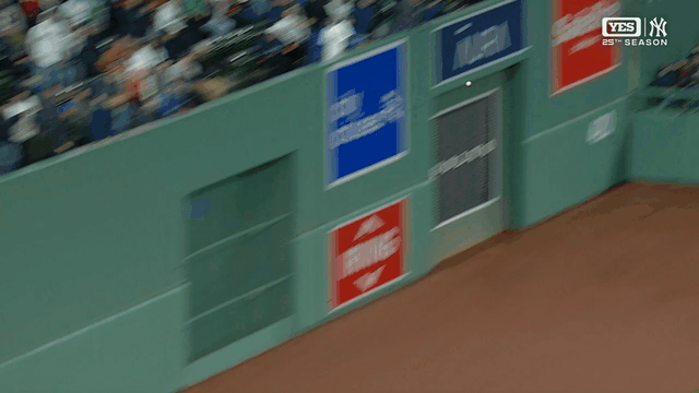 An animated gif of Ceddanne Rafaela leaping to make a catch and crashing into Boston's green wall