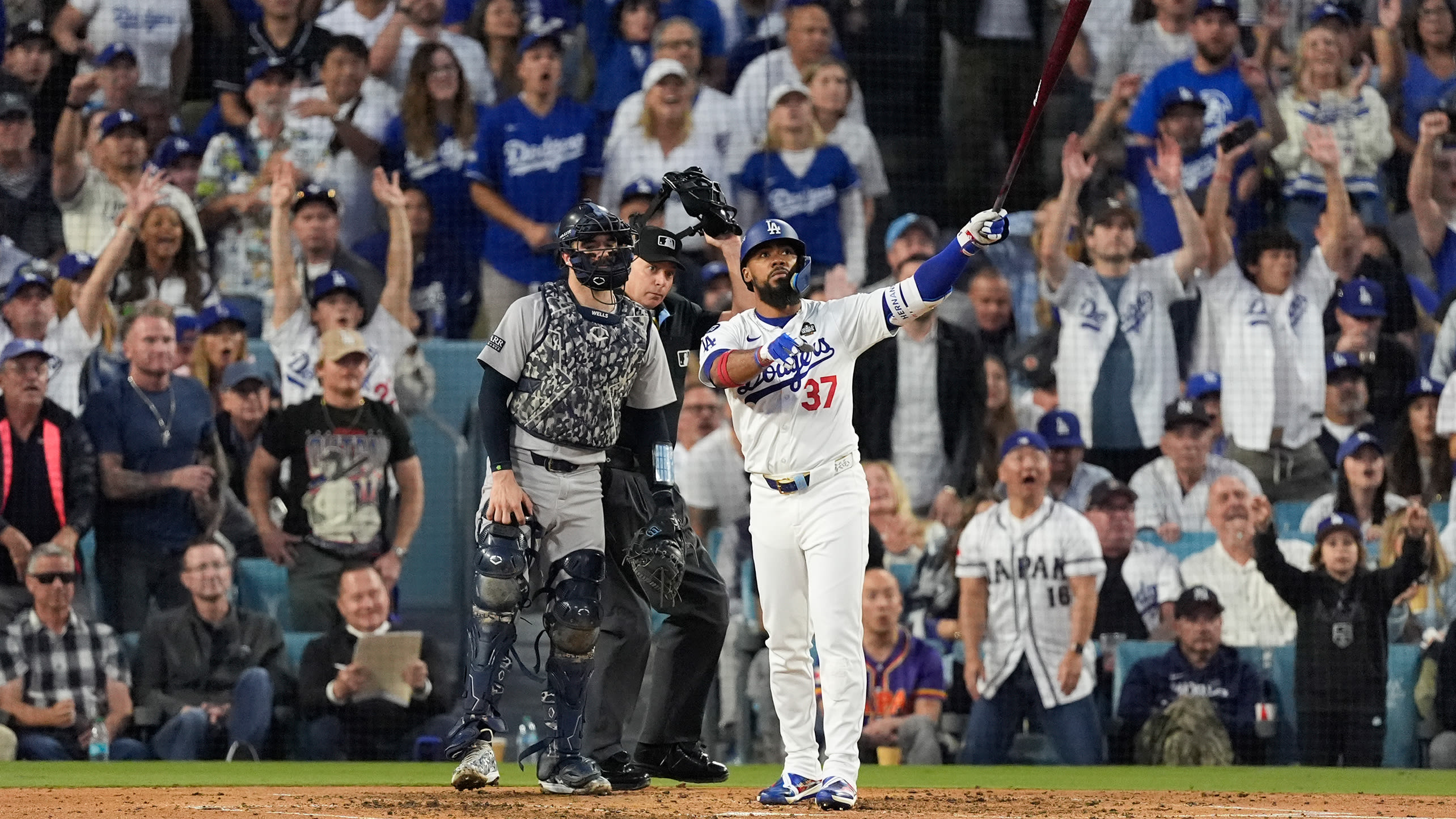 Teoscar Hernández stands with his bat raised as his two-run home run soars toward the seats