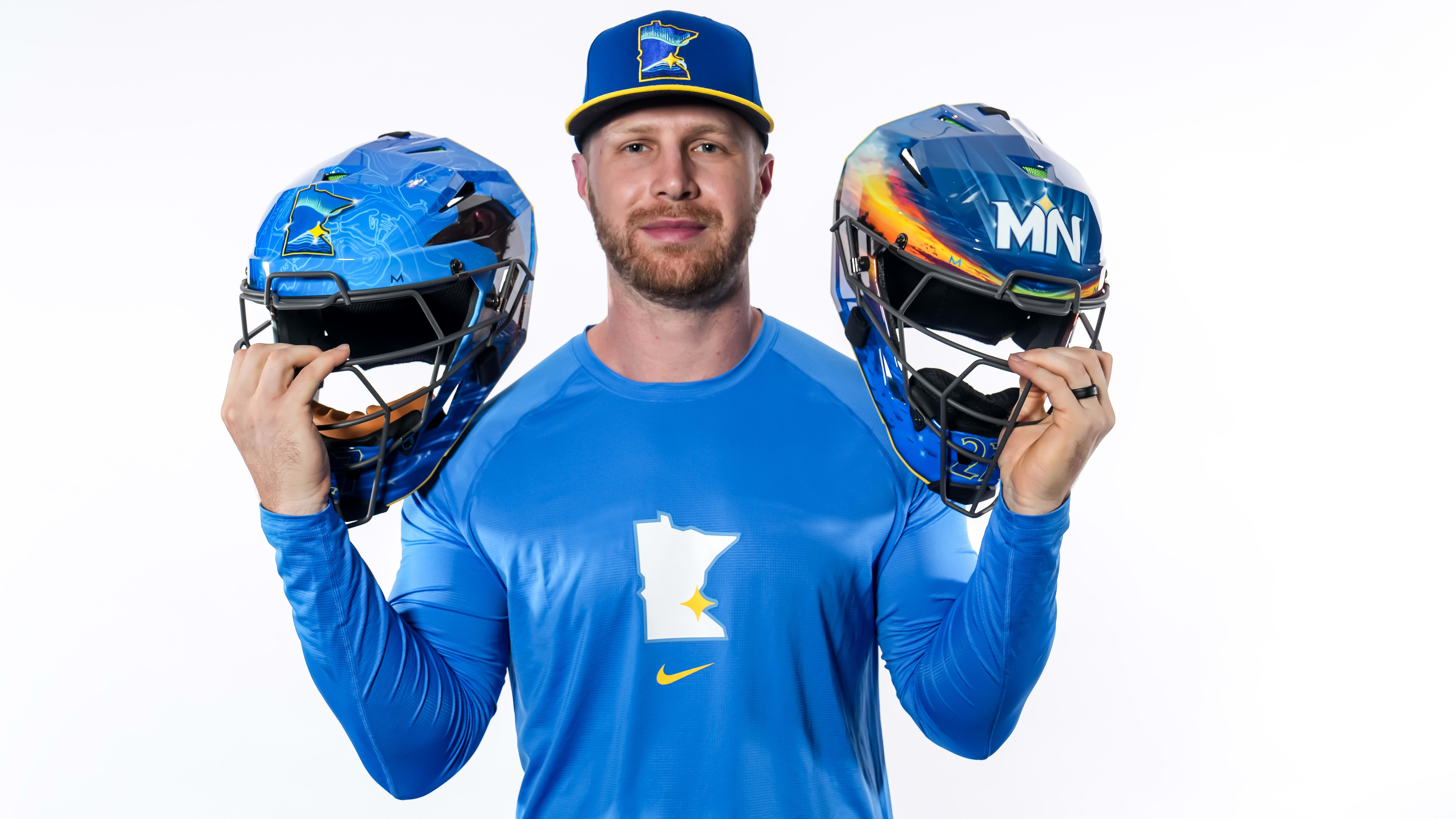 Ryan Jeffers holds up two custom helmets