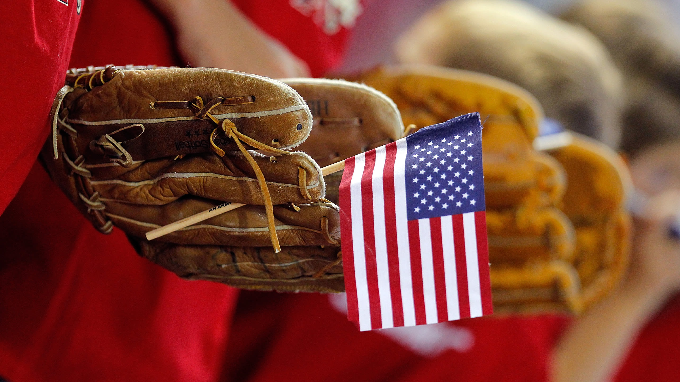 A baseball glove holding a mini American flag