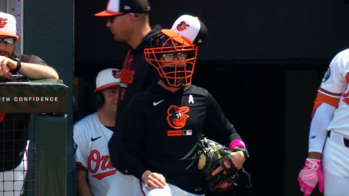 Orioles manager Craig Albernaz wears a catcher's mask and glove