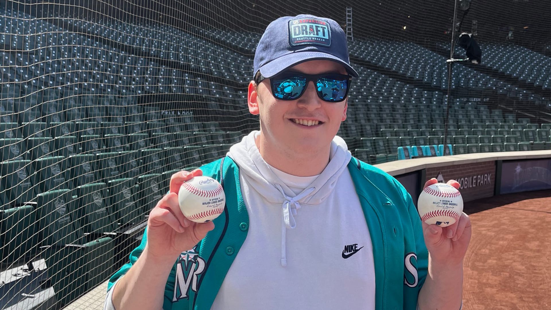 Mariners fan Josh George holds up two baseballs