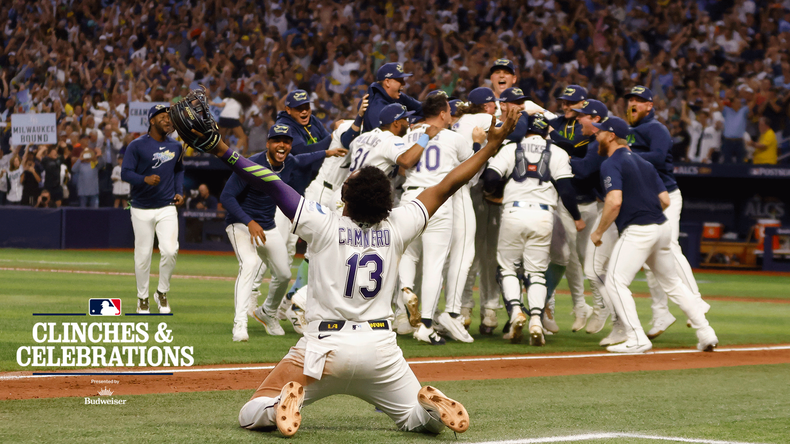 Junior Caminero drops to his knees and looks skyward as the Rays celebrate on the infield