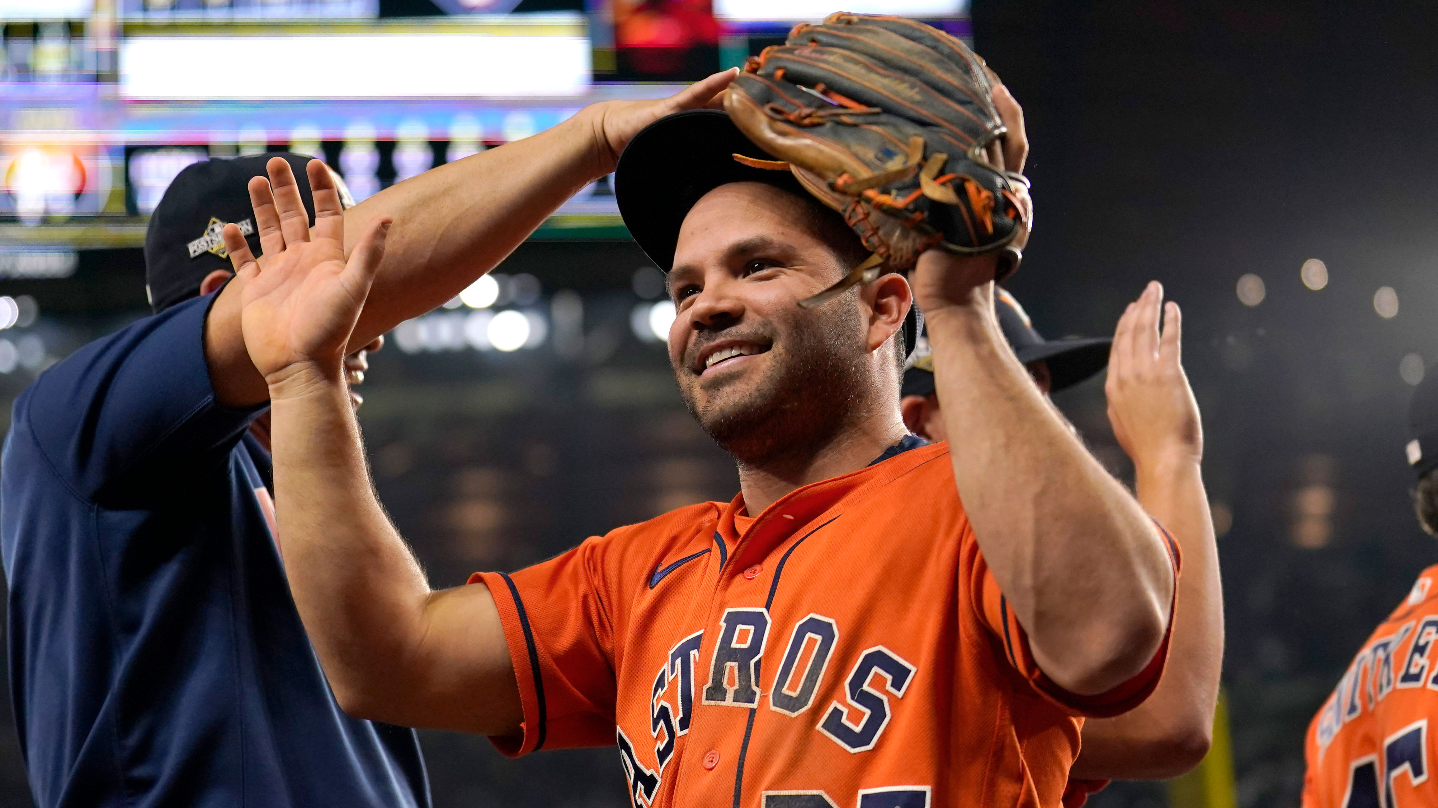 Jose Altuve smiles and raises his arms as a teammate pats him on the head