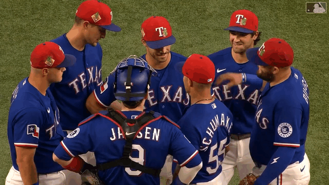 An animated gif of Rangers players patting a smiling Carter Baumler on the back during a mound visit
