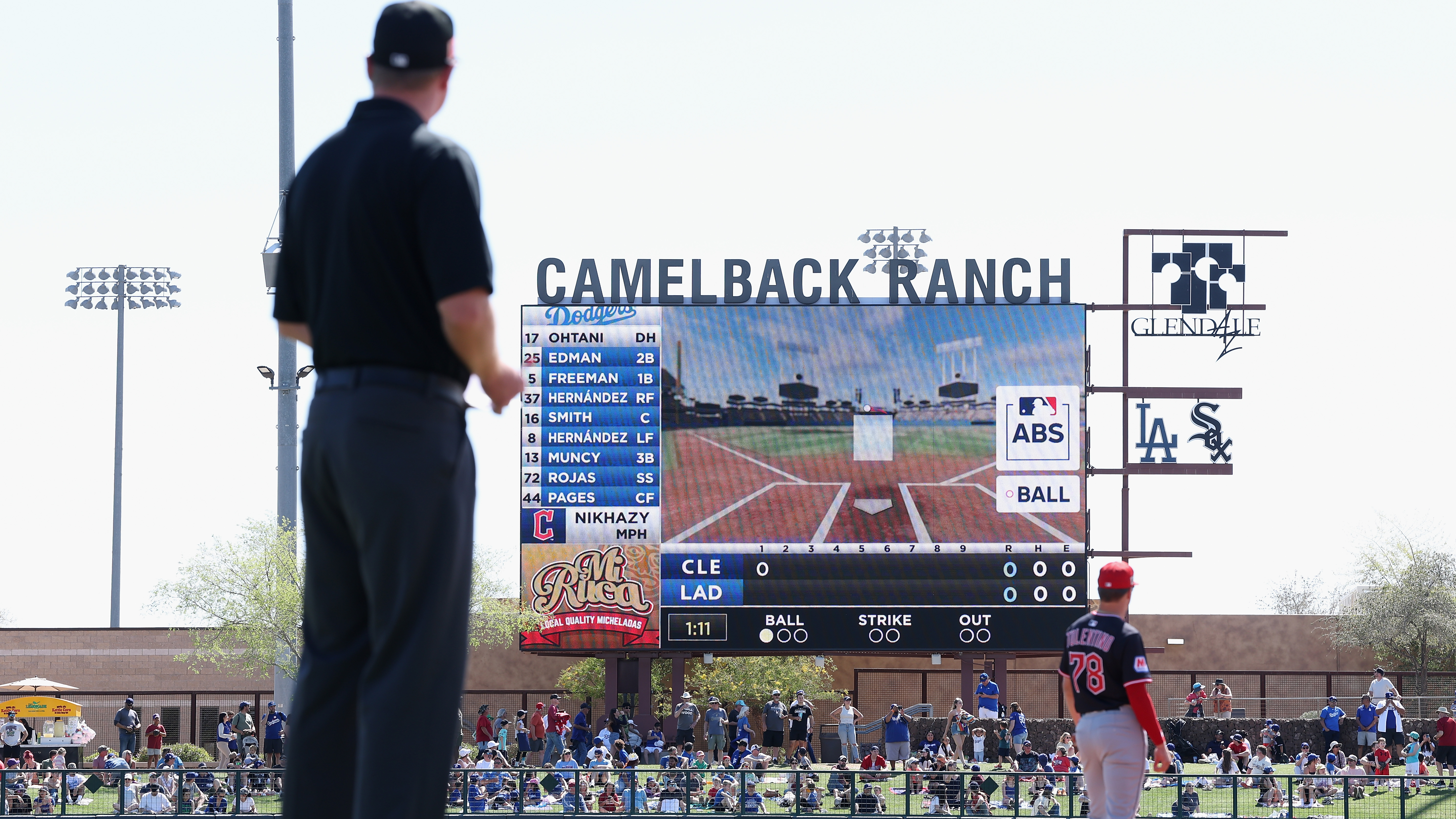 An umpire and fielder look at an ABS challenge on a ballpark video board in Spring Training