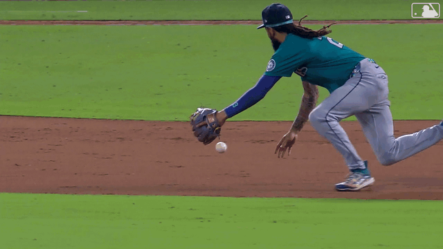 An animated gif of Mariners shortstop J.P. Crawford making a sliding stop and flipping the ball with his glove to the second baseman for a relay to first base
