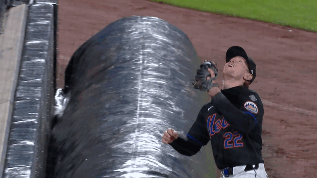 Brett Baty tumbles over the tarp to make a catch