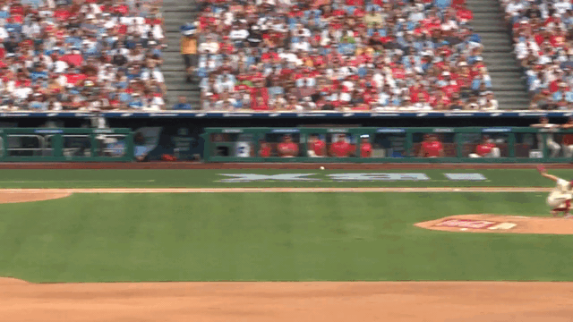 An animated gif of Trea Turner diving for a ball and making a backwards toss to second base to start a double play