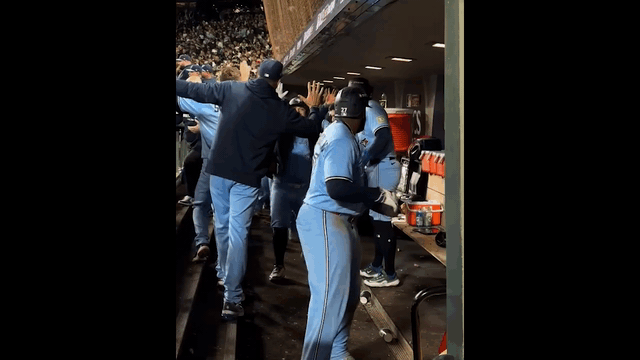 An animated gif of Vladimir Guerrero Jr. and Alejandro Kirk hugging and bouncing in the dugout