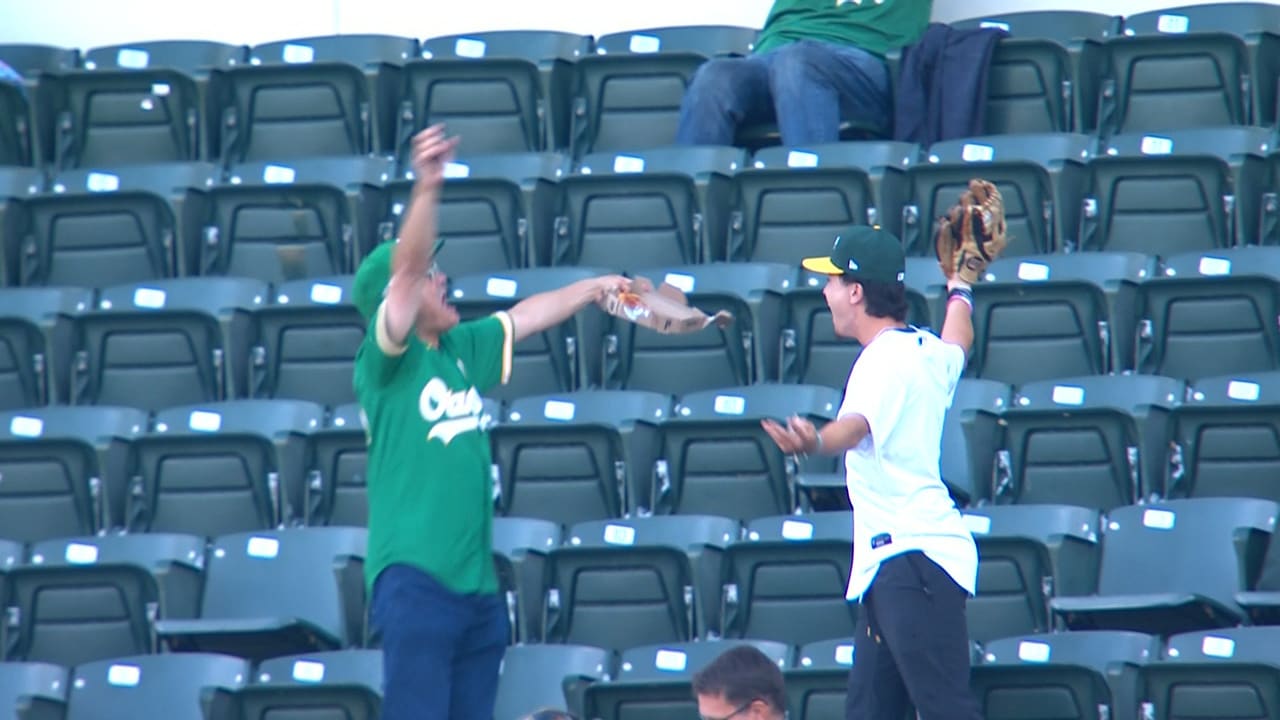 An A's fan celebrates catching three foul balls in one inning