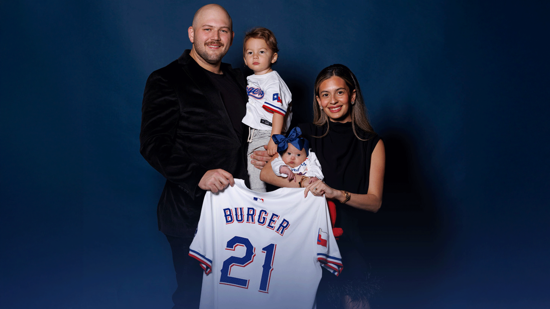 Jake Burger holds up his jersey with his wife and two children