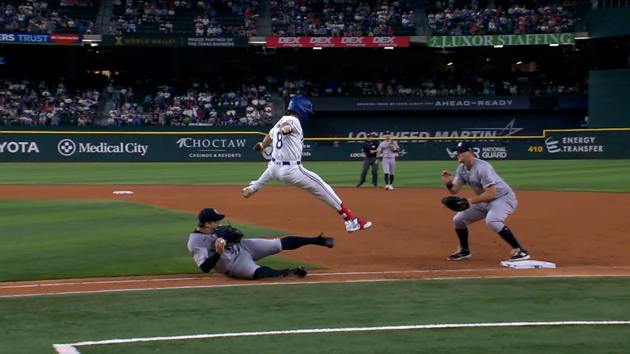 The Rangers' Josh Smith hurdles over Yankees pitcher Tommy Kahnle, who's on the ground in front of first base