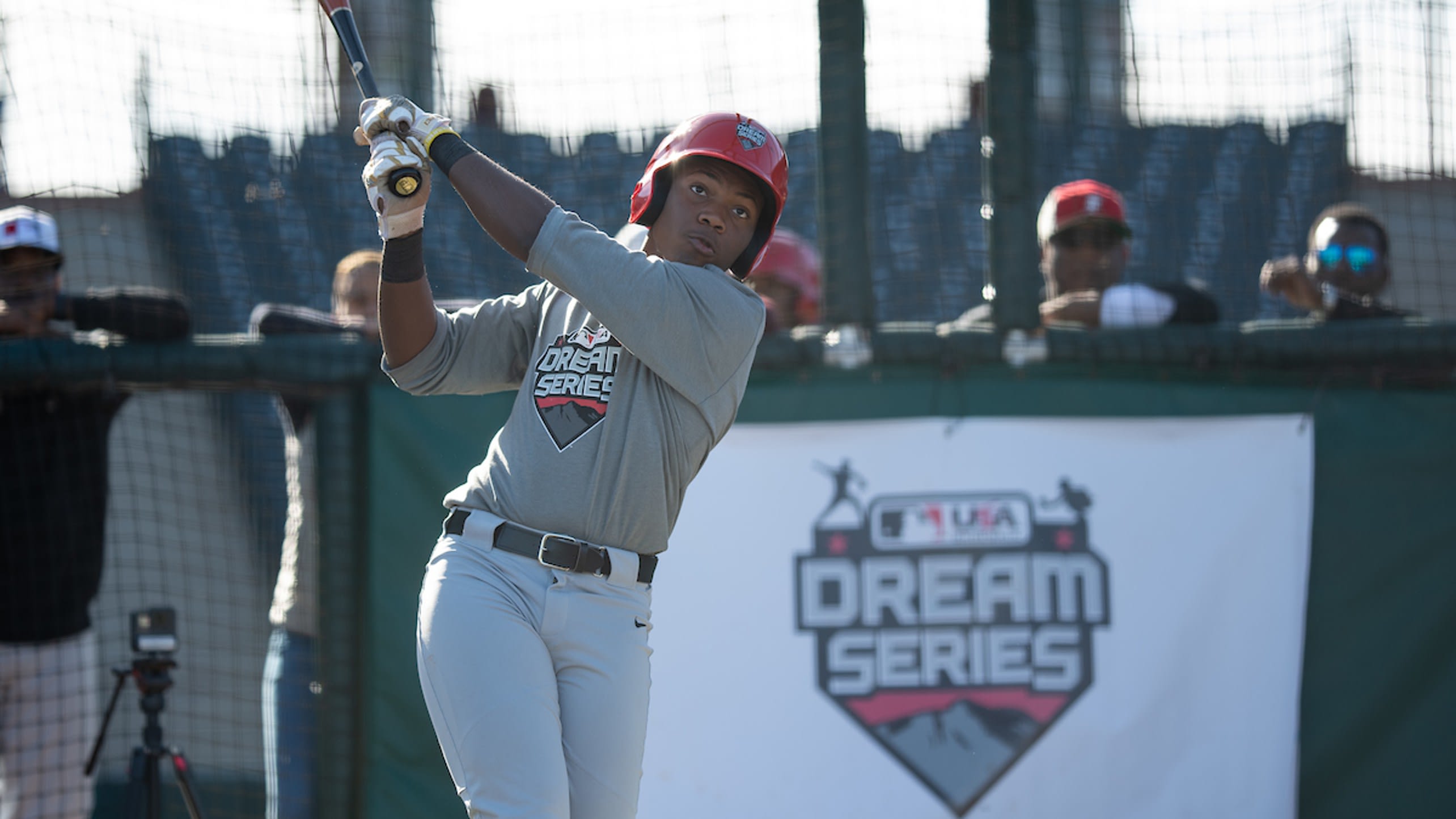 A young players swings a bat in front of a DREAM Series banner