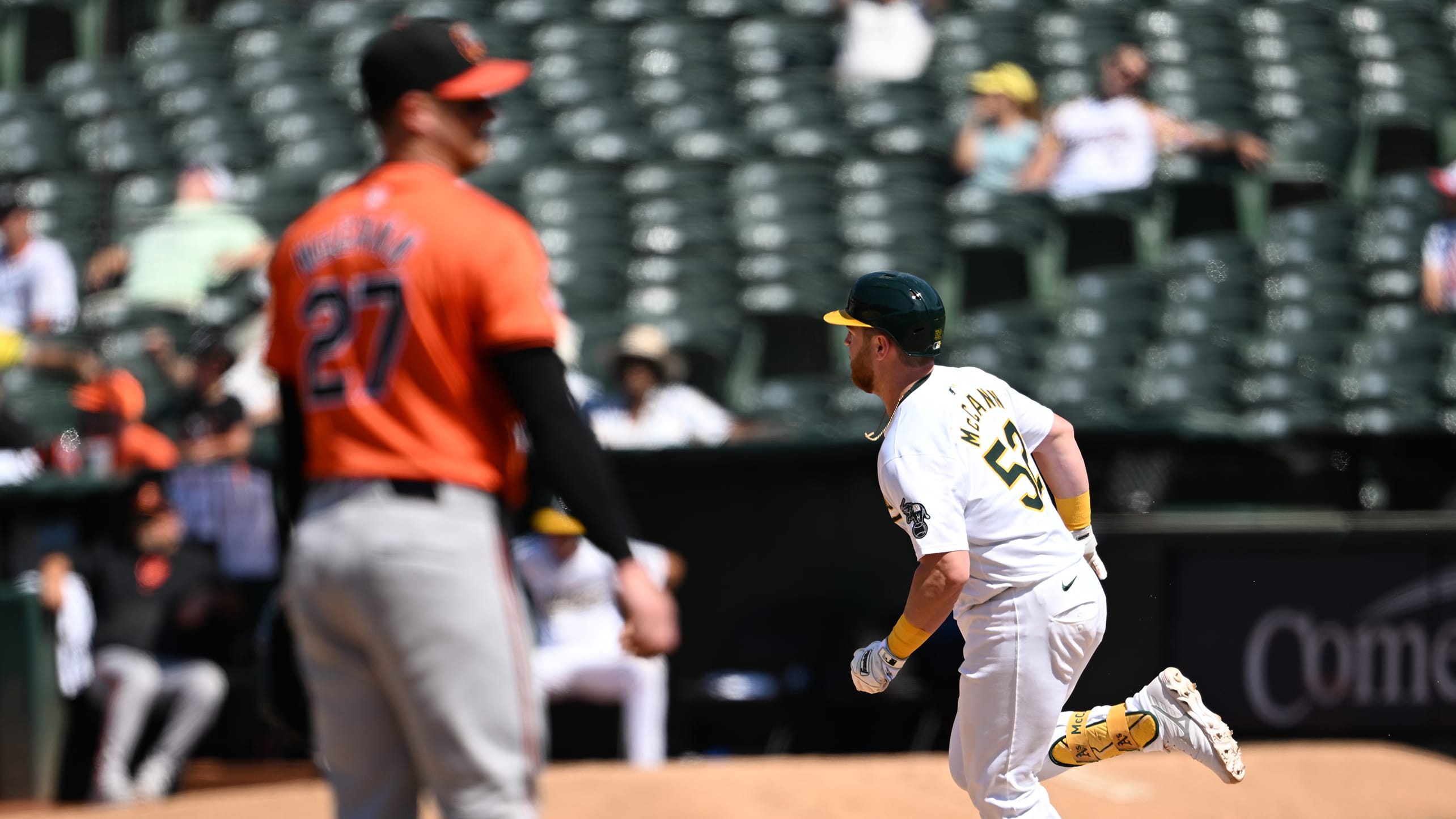 Kyle McCann rounds the bases as James McCann stands on the pitching mound in the foreground