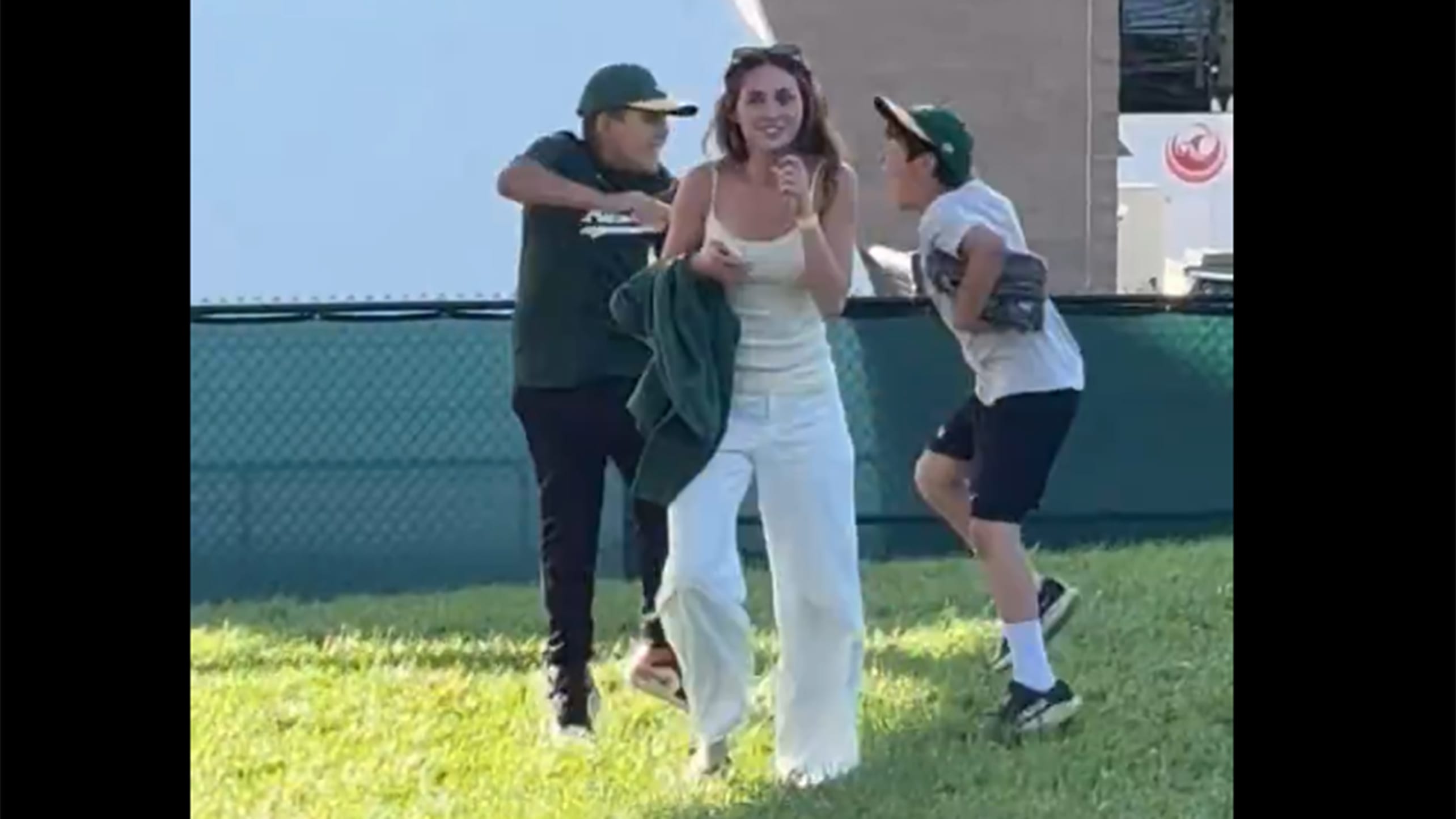 Two young fans jump up and down as a woman walks away from them