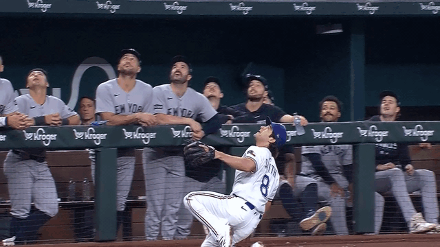 An animated gif of Rangers third baseman Josh Smith making a sliding catch right in front of the Yankees' dugout