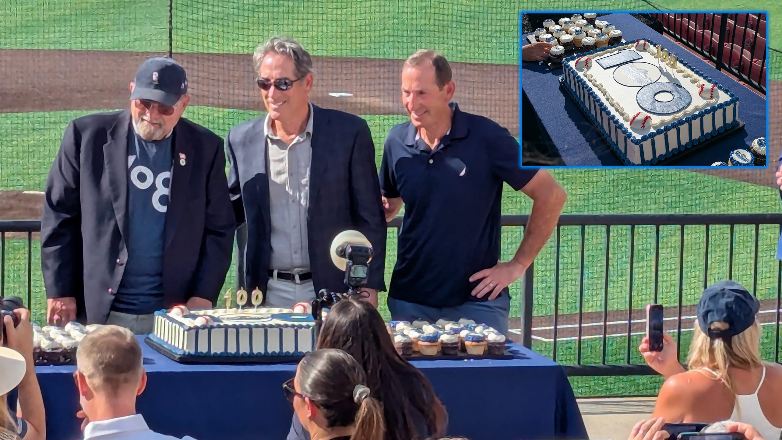 Larry, Tim and Dale Berra stand behind a cake celebrating Yogi Berra's 100th birthday