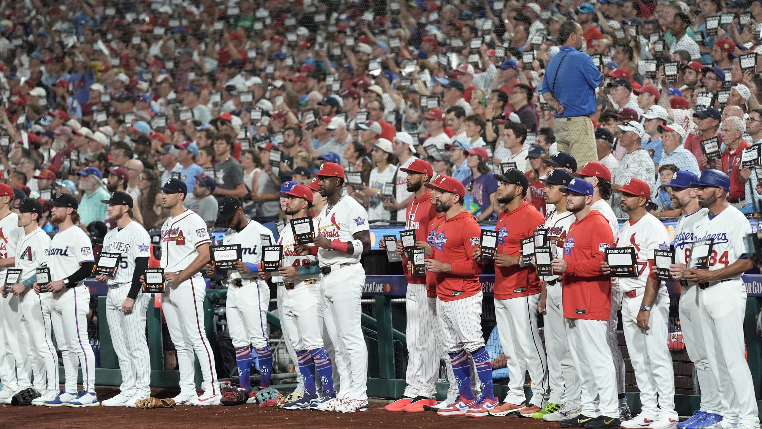 Players hold up Stand Up 2 Cancer signs