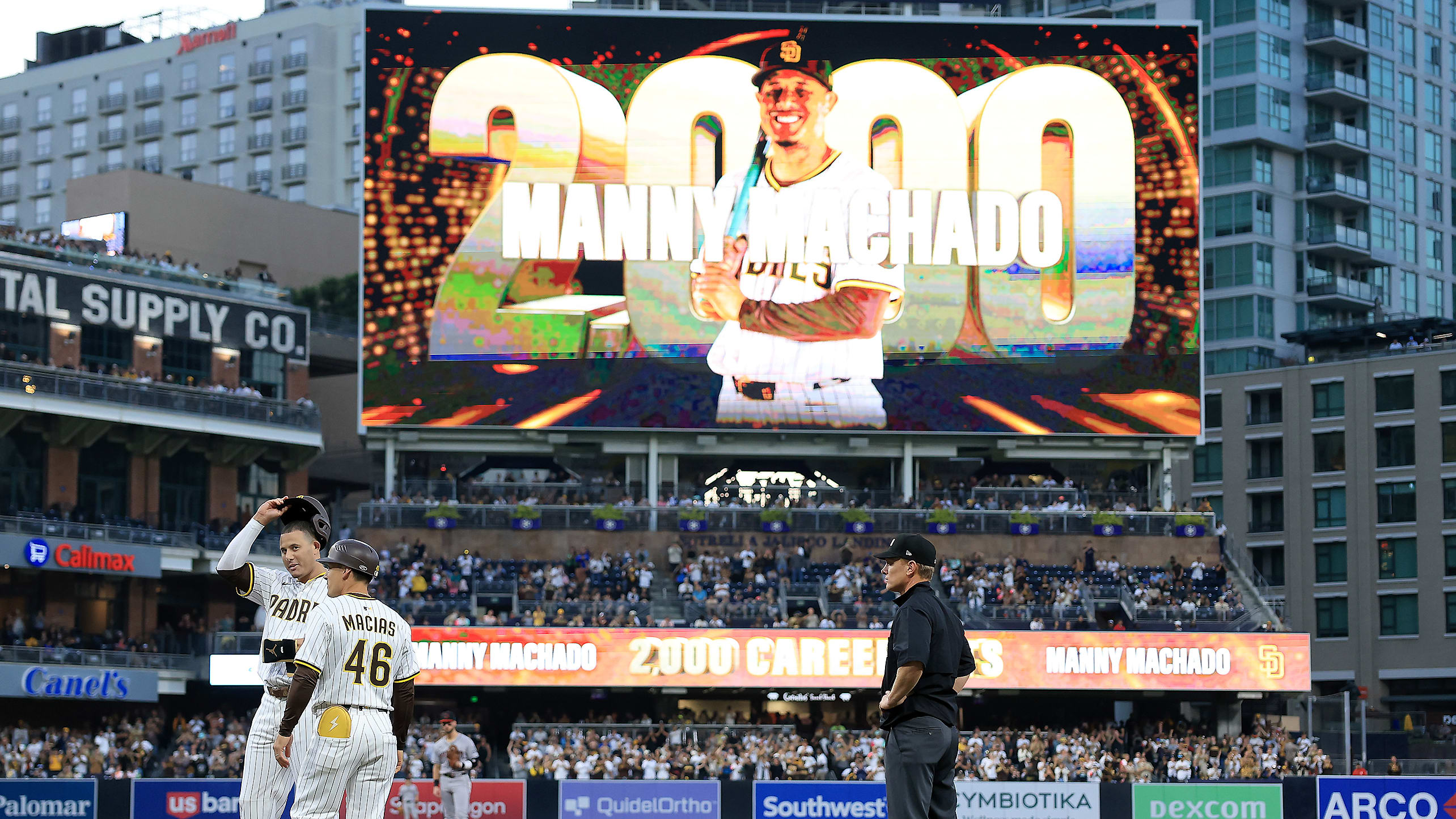 Manny Machado doffs his helmet with a graphic behind him on the scoreboard celebrating his 2,000th hit