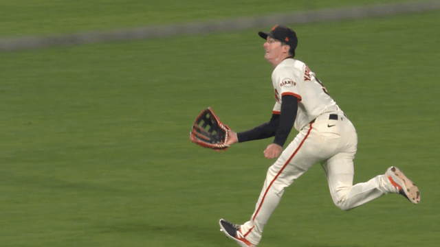 Mike Yastrzemski reaches down to catch a ball just before it hits the ground