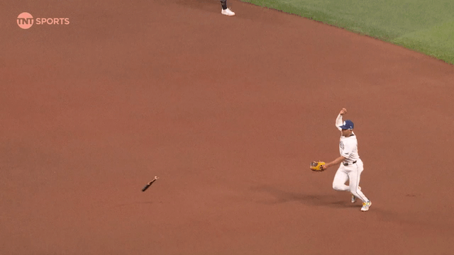 An animated gif of Richie Palacios fielding a grounder while a broken bat flies his way