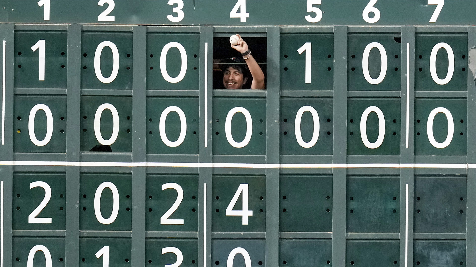 A scoreboard operator holds up a baseball