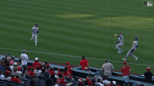 Bobby Witt Jr. slides between two teammates to make a catch