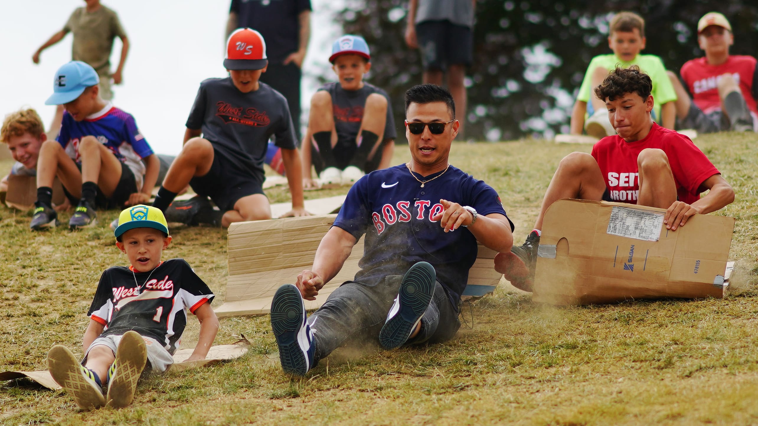 Red Sox player Rob Refsnyder and Little Leaguers slide down a hill