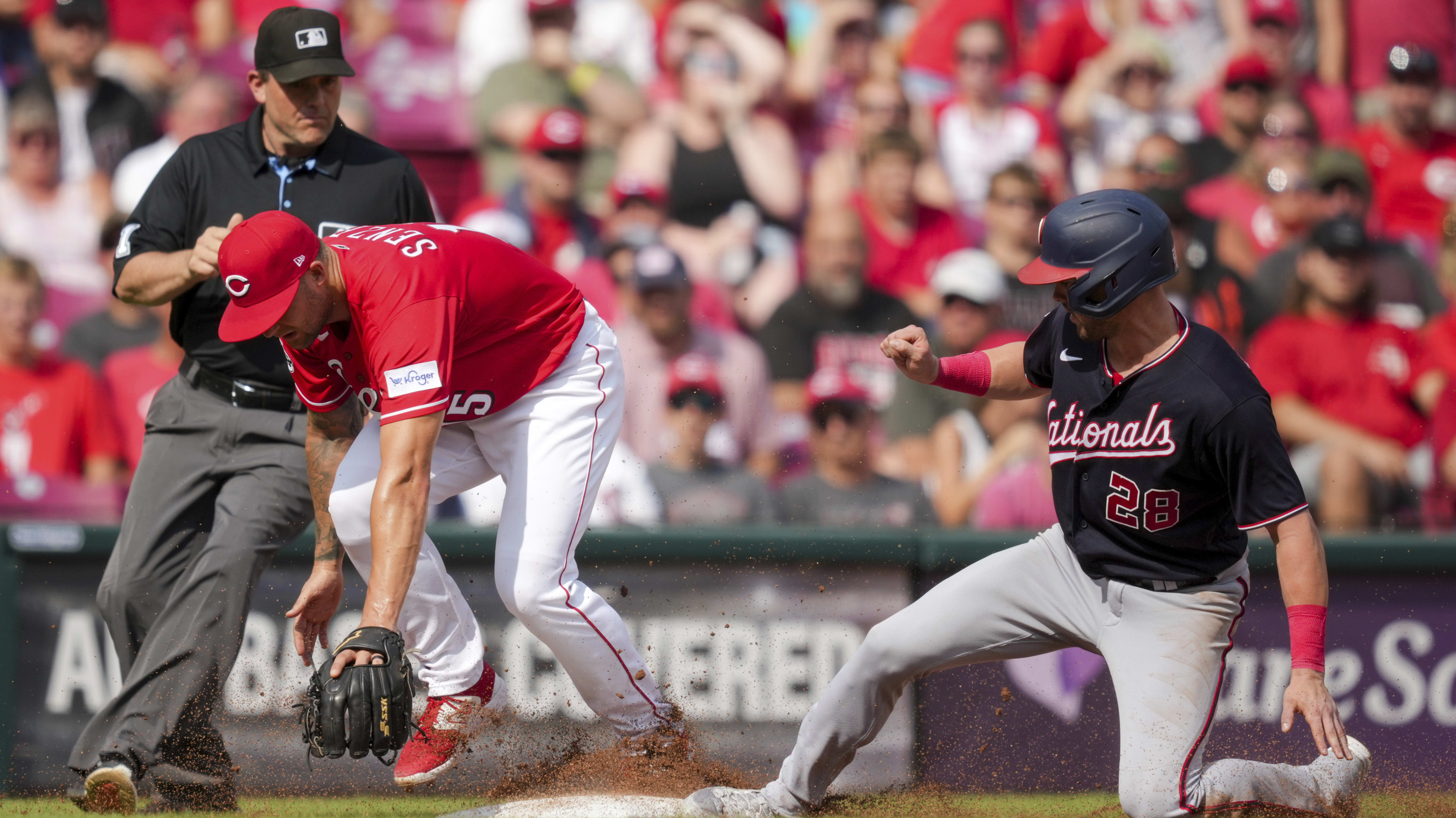 Nick Senzel, then with the Reds, steps on third base as Lane Thomas of the Nationals slides in