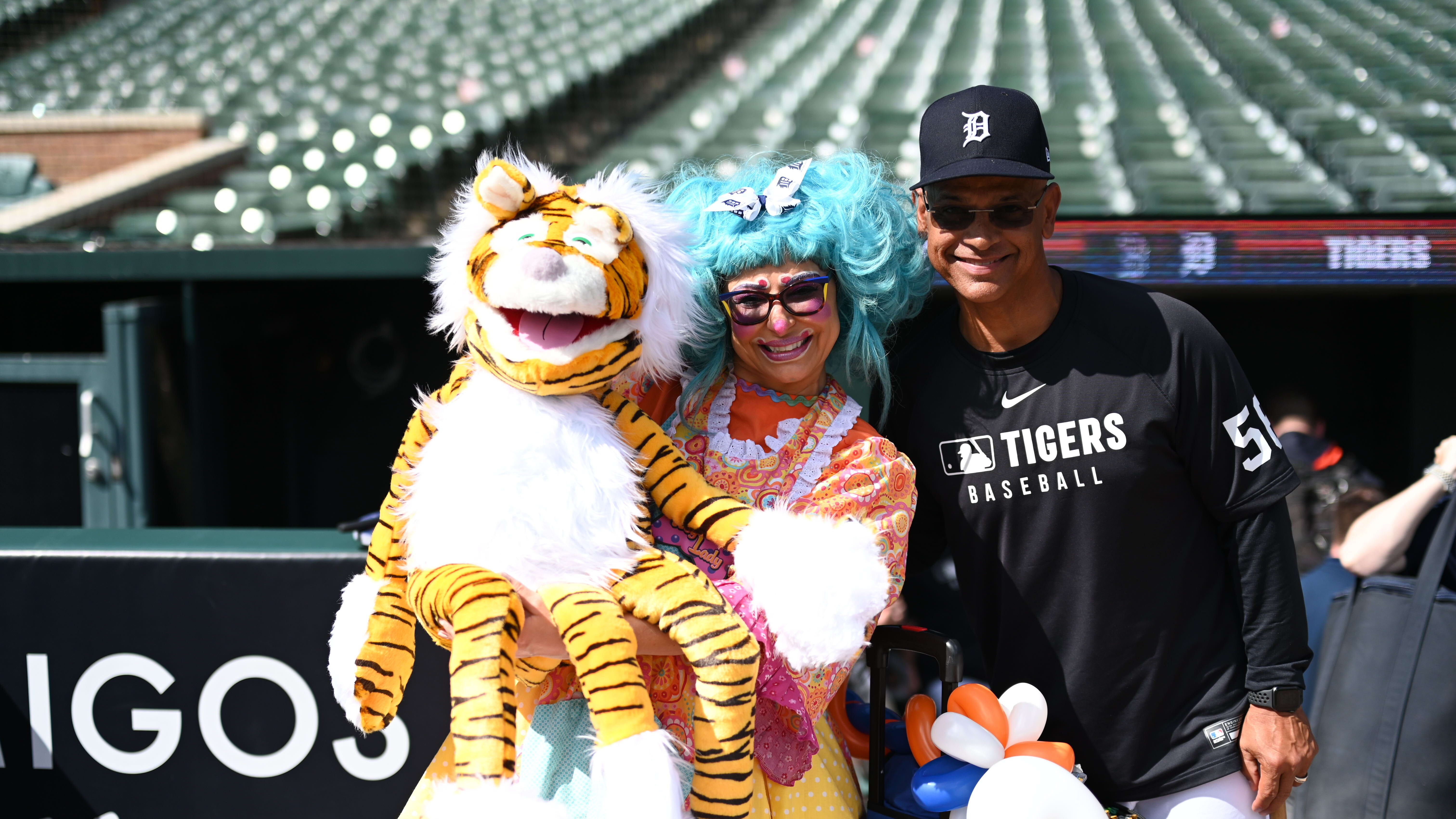 Tigers coach Joey Cora smiles with a clown holding a puppet