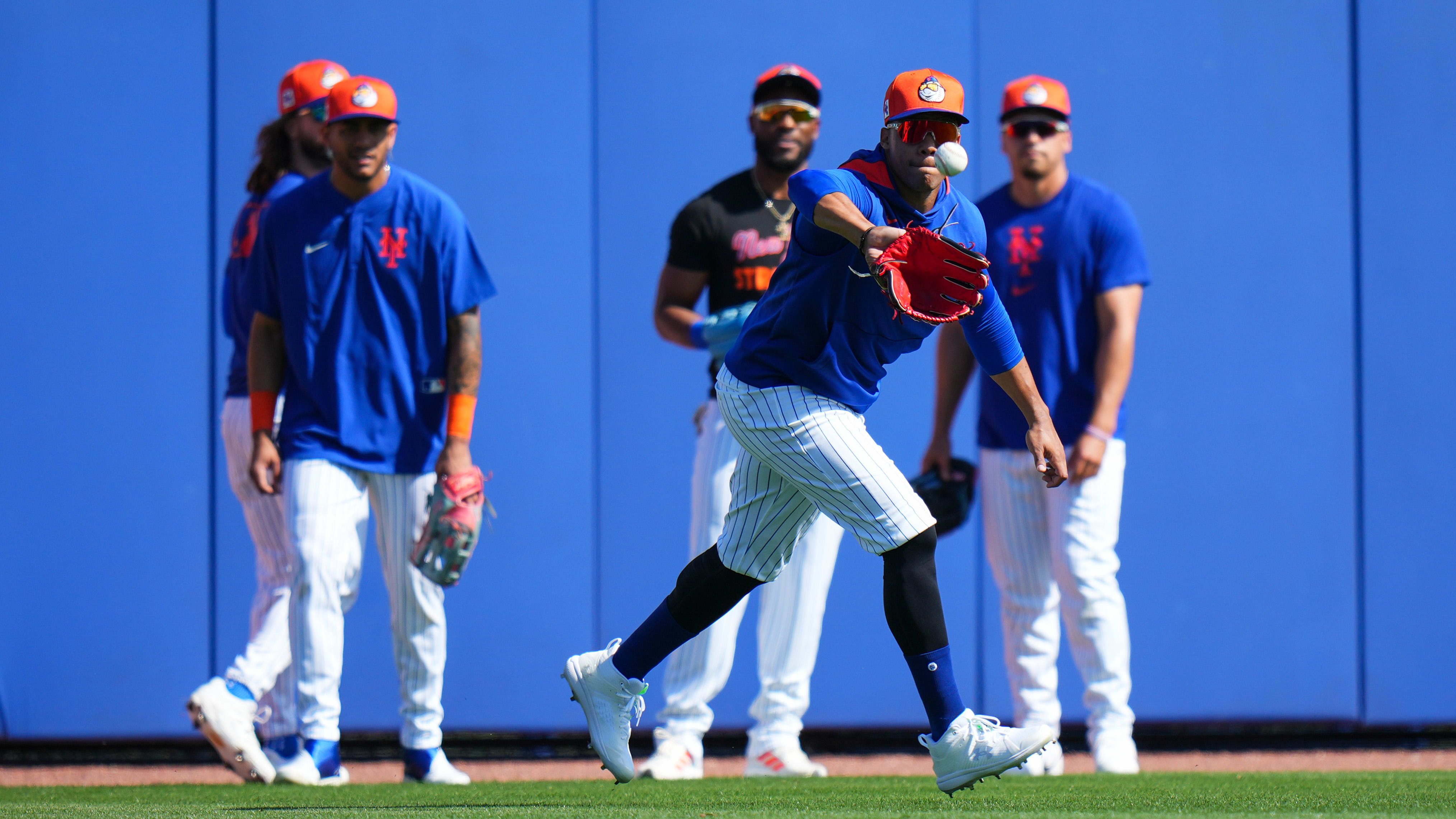 Juan Soto catches a fly ball during outfield drills as four other players look on