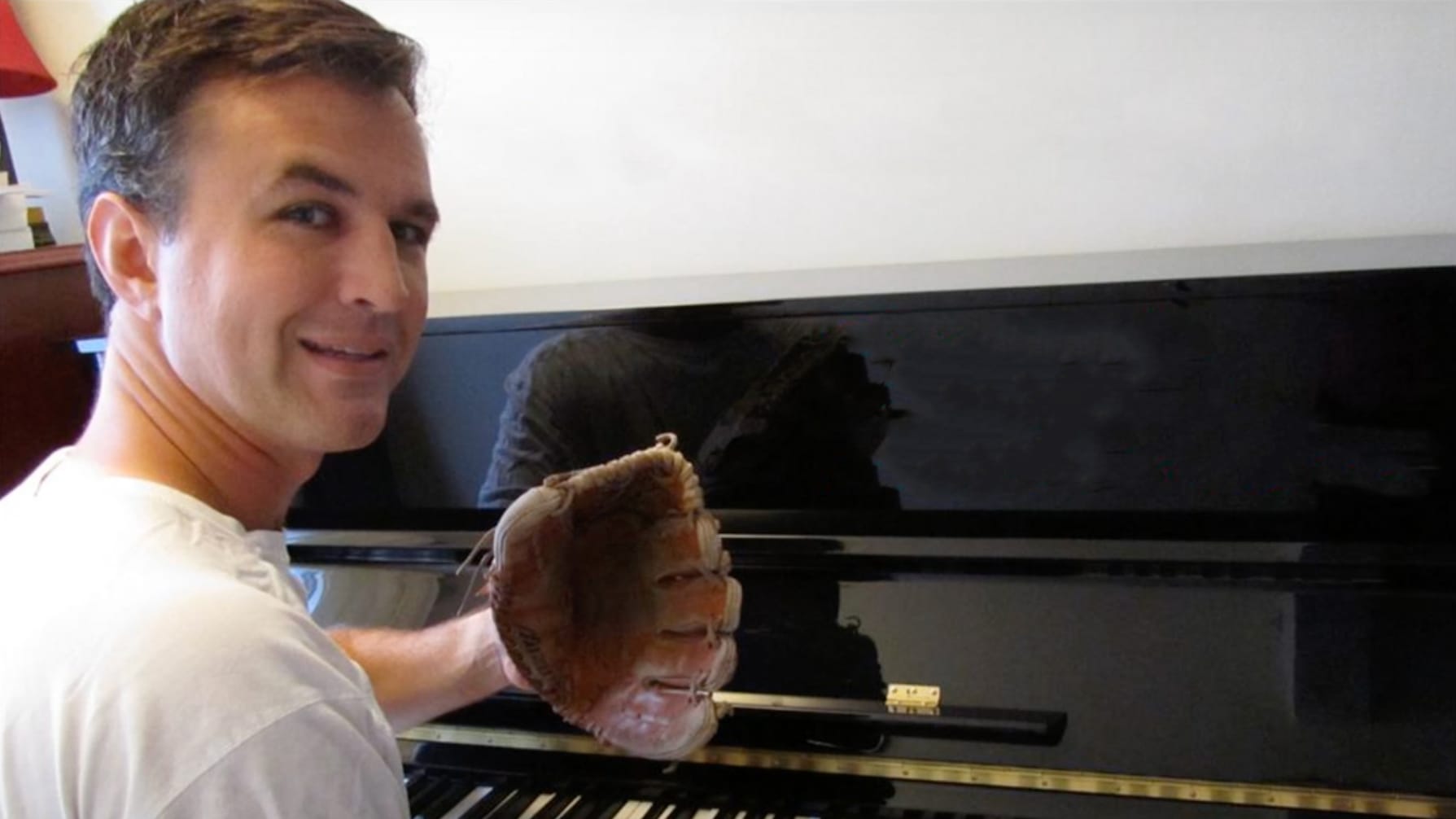 Musician Matt Farley with a baseball glove at the piano