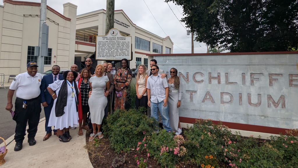 State and local representatives celebrate the unveiling of a marker outside the Charles J. Muth Museum of Hinchliffe Stadium.