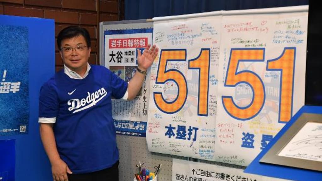 Oshu Mayor Jun Kuranari poses in front of the Shohei Ohtani home run and stolen base tracker.