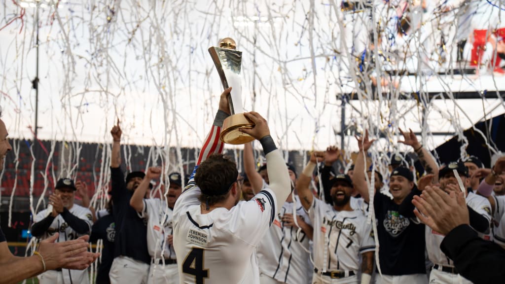Claudio Finol lifts the Baseball Champions League trophy aloft for his Kane County Cougars teammates. Photo courtesy the American Association.