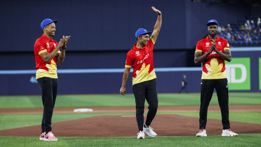 Saad Zafar waves after throwing out the ceremonial first pitch with teammates Nicholas Kirton (left) and Jeremy Gordon (right)